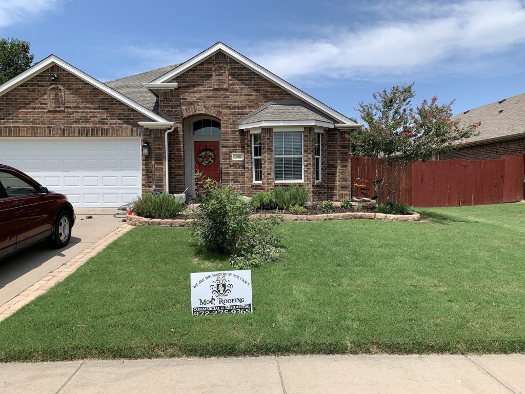 Residential home with manicured garden and roofing sign